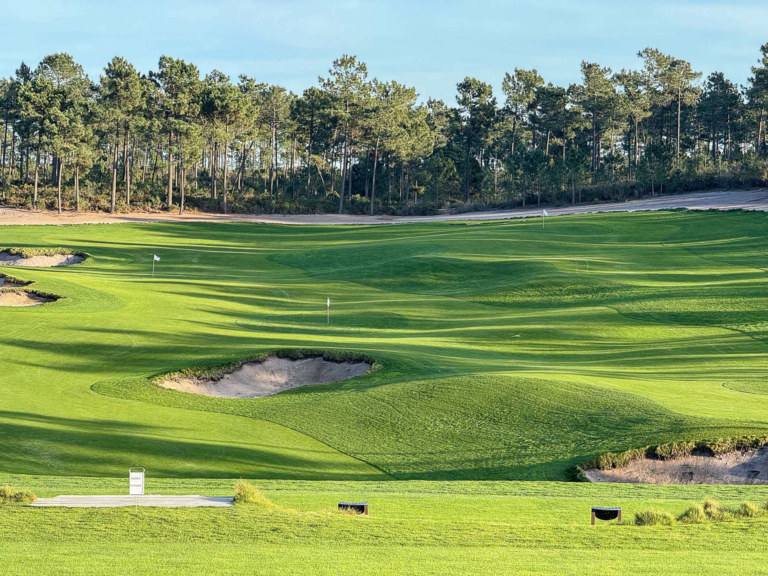 Ein Golfer beim Abschlag auf dem weitläufigen grünen Dunas Course unter blauem Himmel.