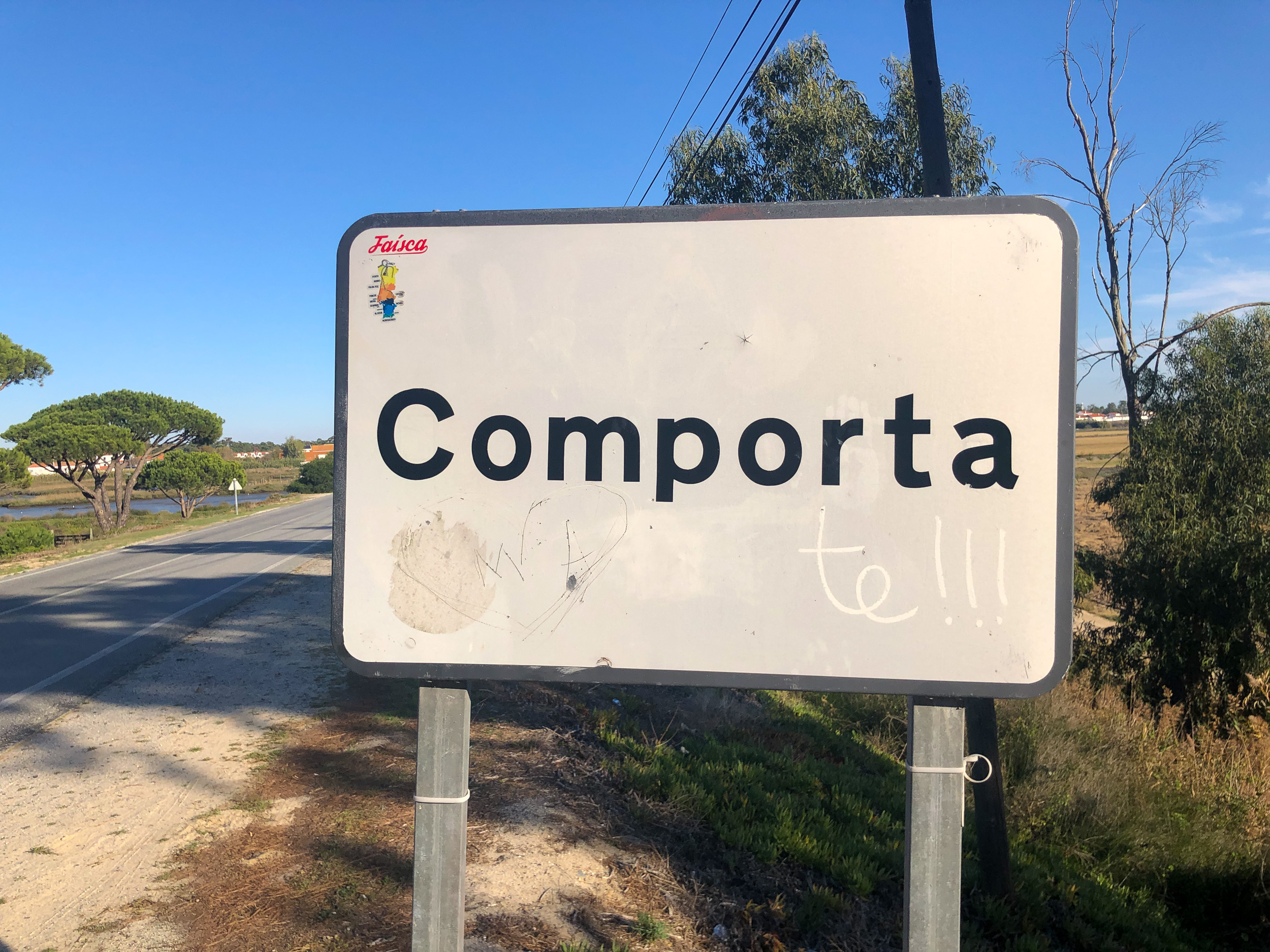 Le panneau blanc du village de Comporta sur la route de campagne sous un ciel bleu éclatant.