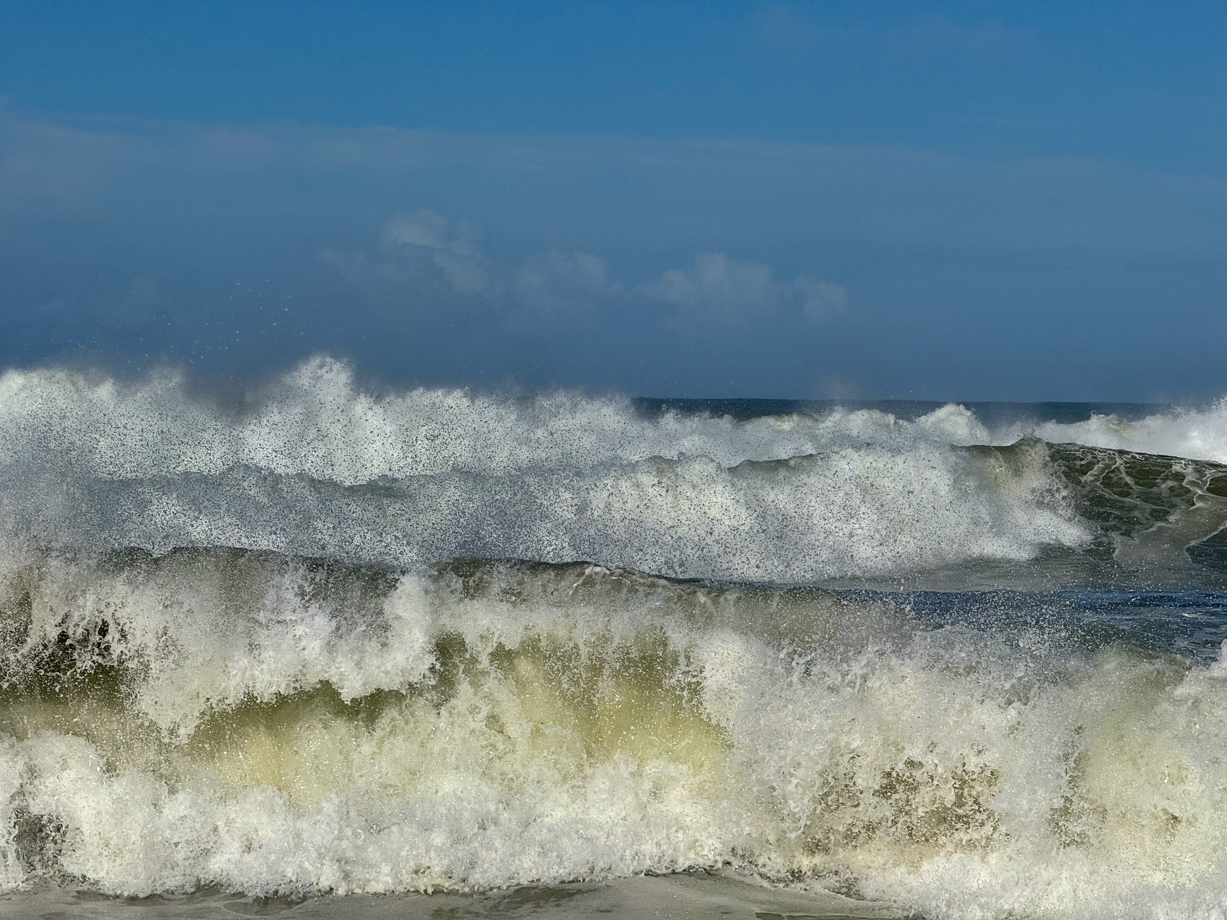 De douces vagues blanches de l'Atlantique roulent sur la plage de sable plat de Carvalhal.