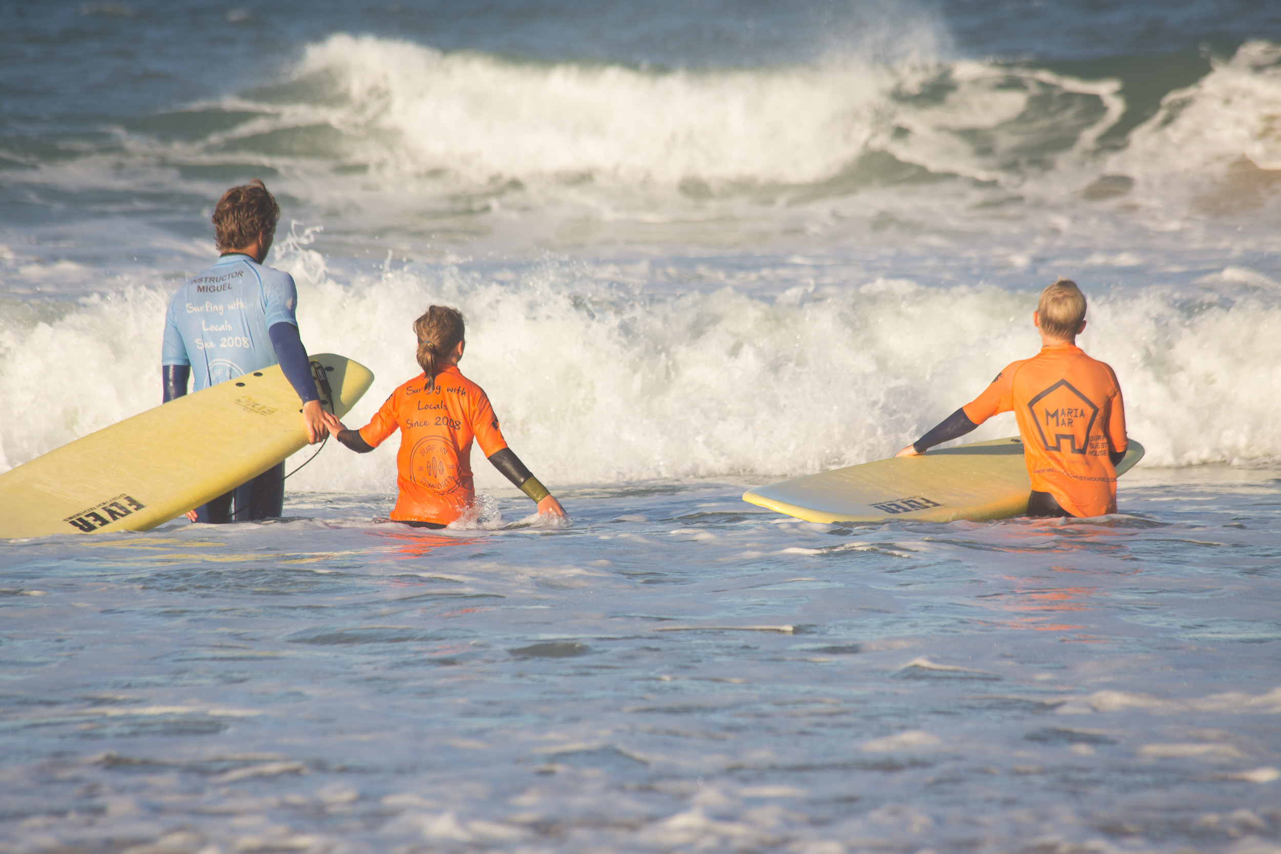 Un moniteur de surf dans l'eau aide patiemment un enfant sur sa planche de surf.