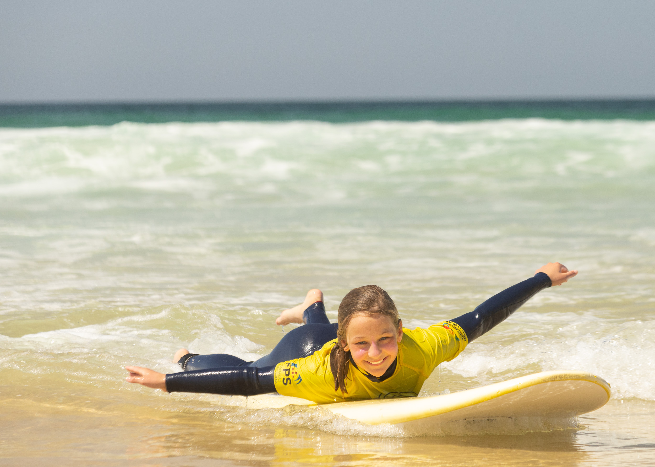 Des enfants rayonnants en combinaisons rient ensemble dans l'eau.