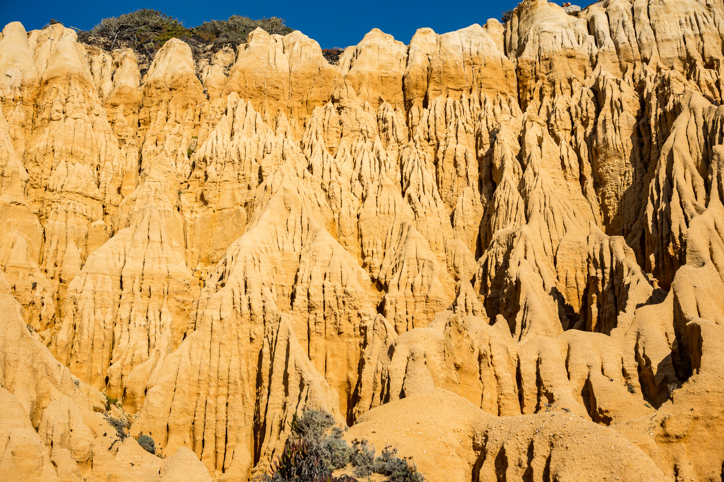 Les hautes falaises s'élèvent presque comme un amphithéâtre naturel semi-circulaire autour de la plage de sable plat.