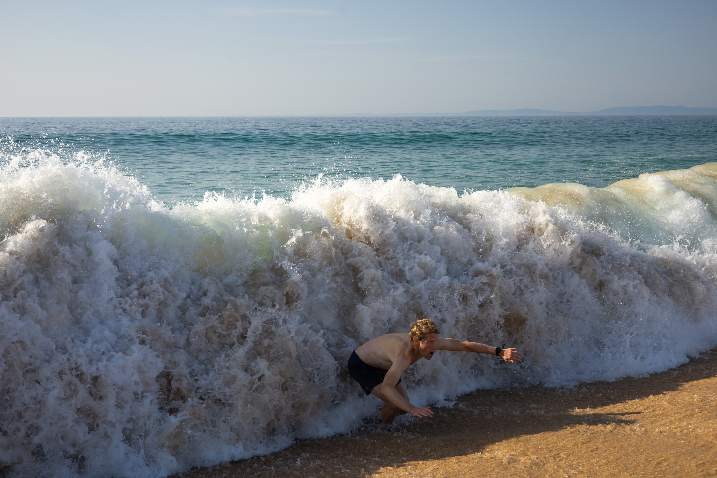 Une planche de SUP repose prête sur la plage au bord de l'eau peu profonde de la lagune.