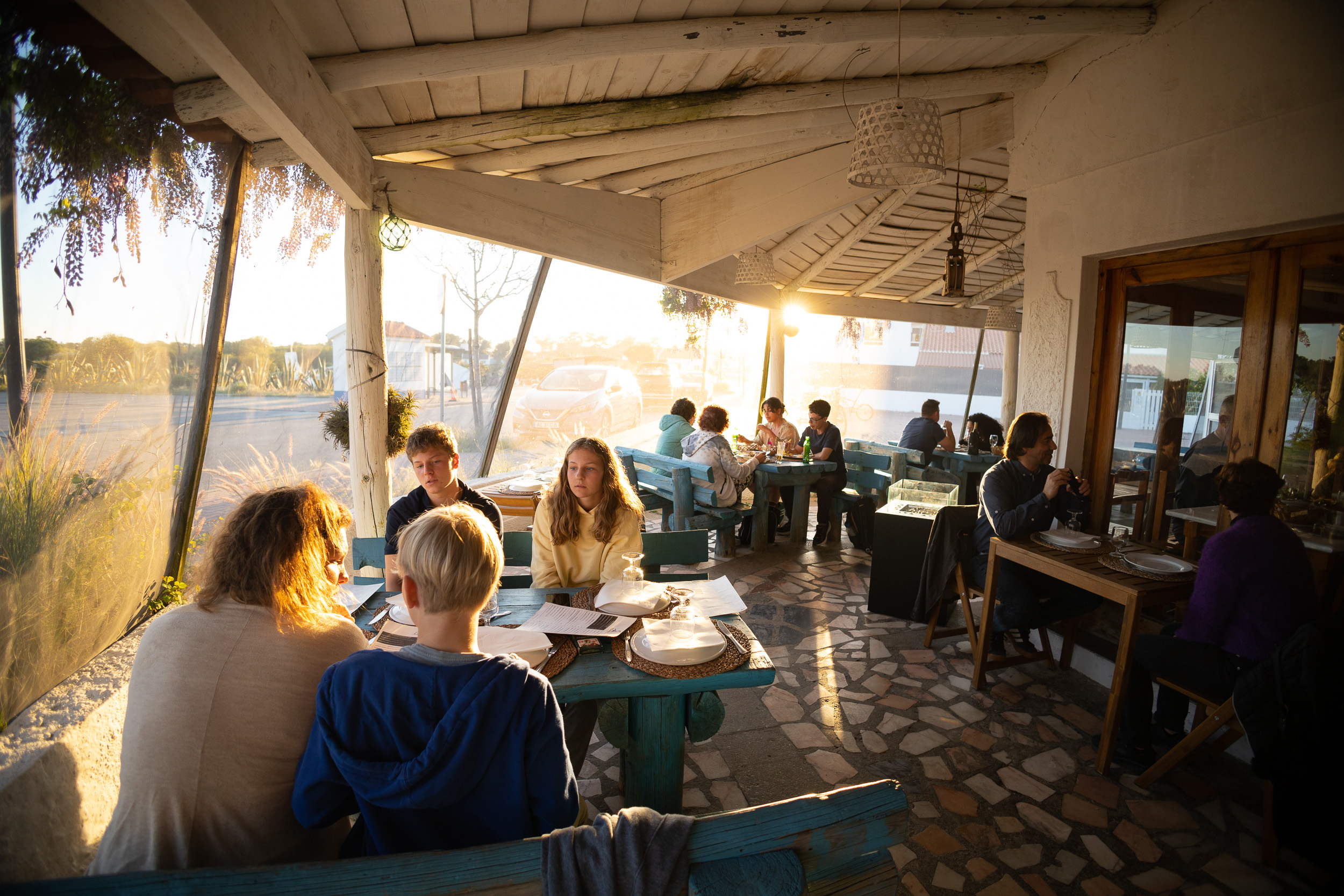 Une terrasse extérieure couverte avec plusieurs tables dans la lumière chaude de la fin d'après-midi.