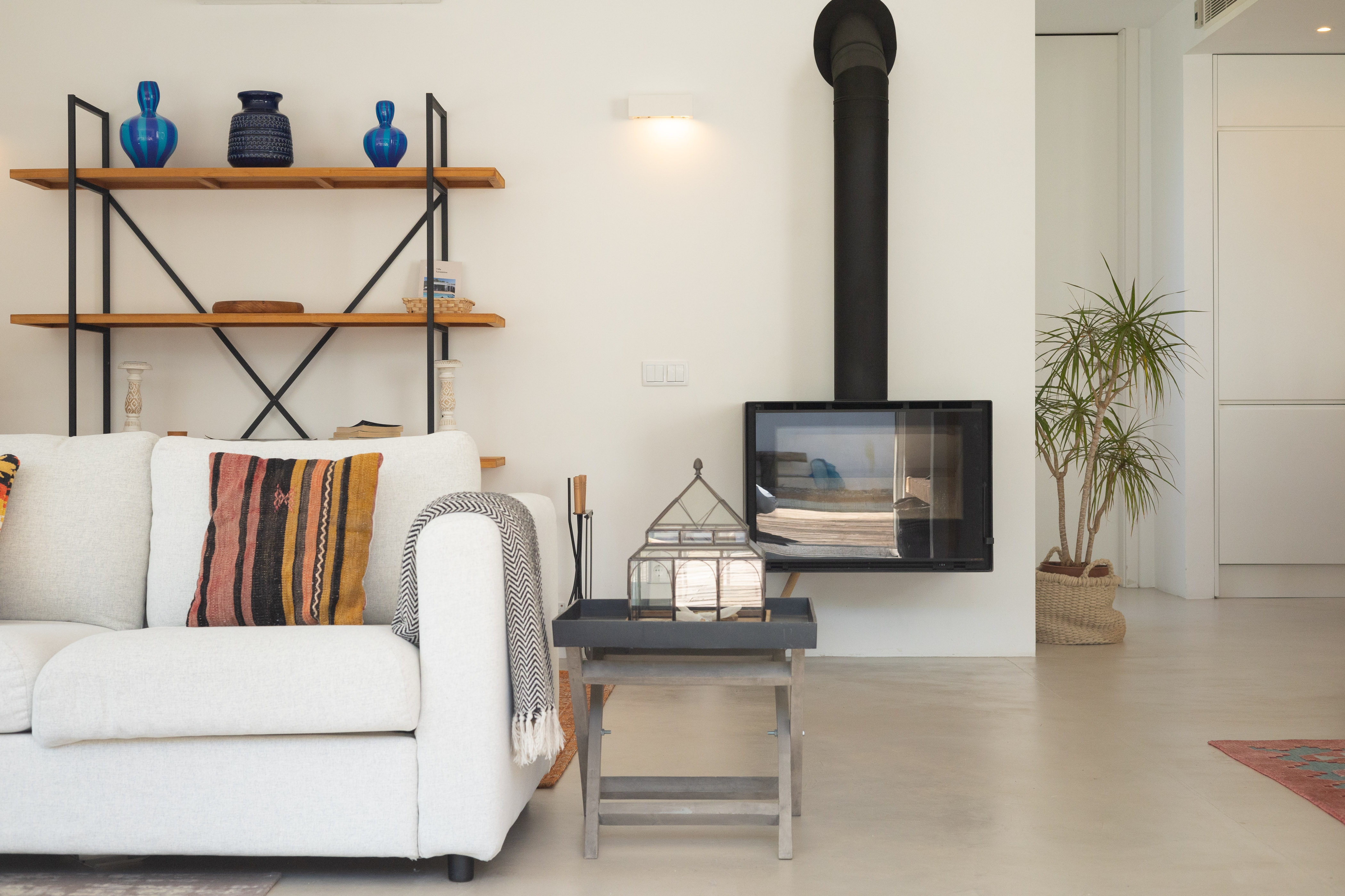 Ein moderner, mit einer Glasscheibe geschlossener Kamin im Wohnzimmer, umgeben von gemütlichen Sofas und einem Couchtisch.