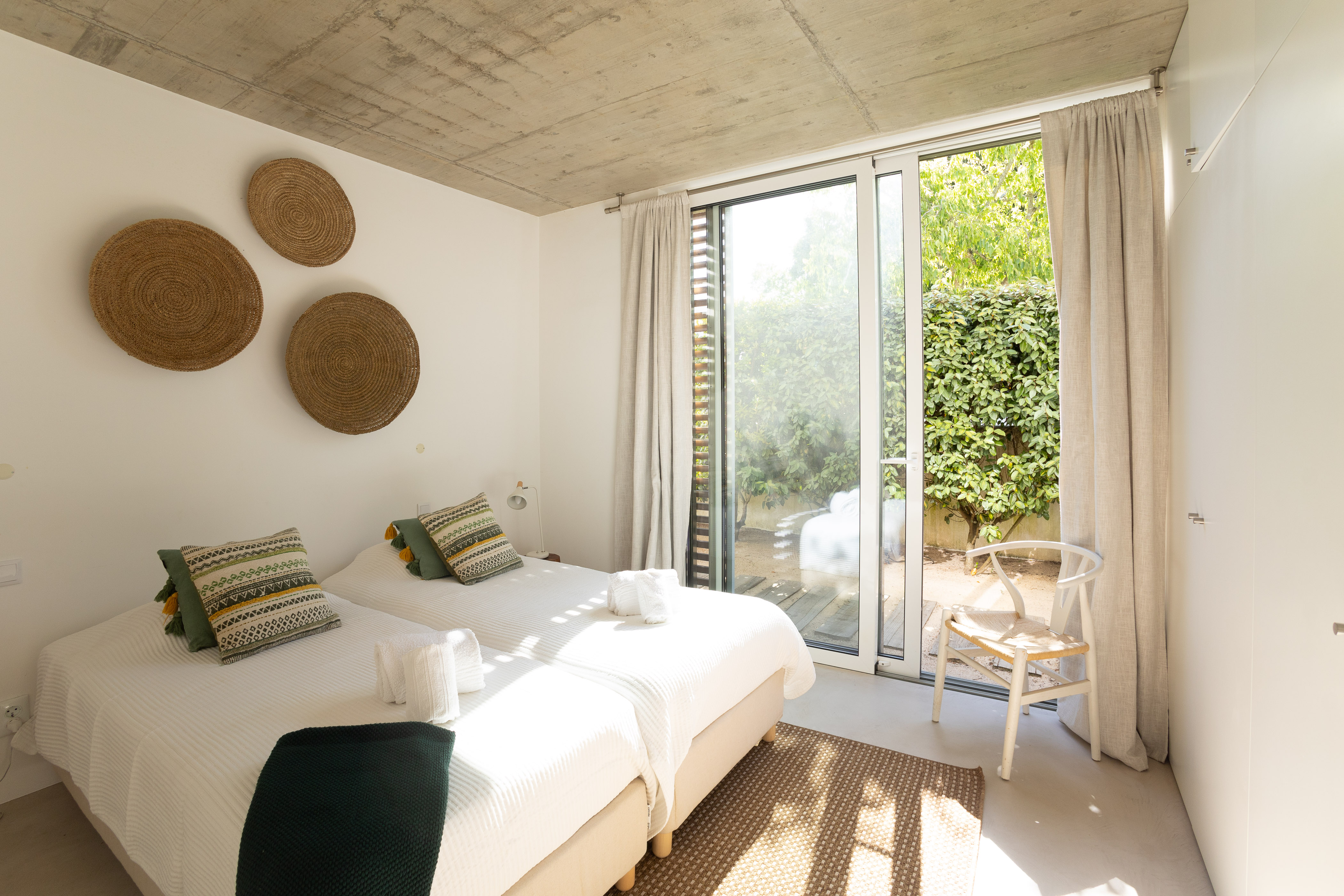 Ein großzügiges Schlafzimmer mit einem Doppelbett, minimalistischer Einrichtung und Gartenblick