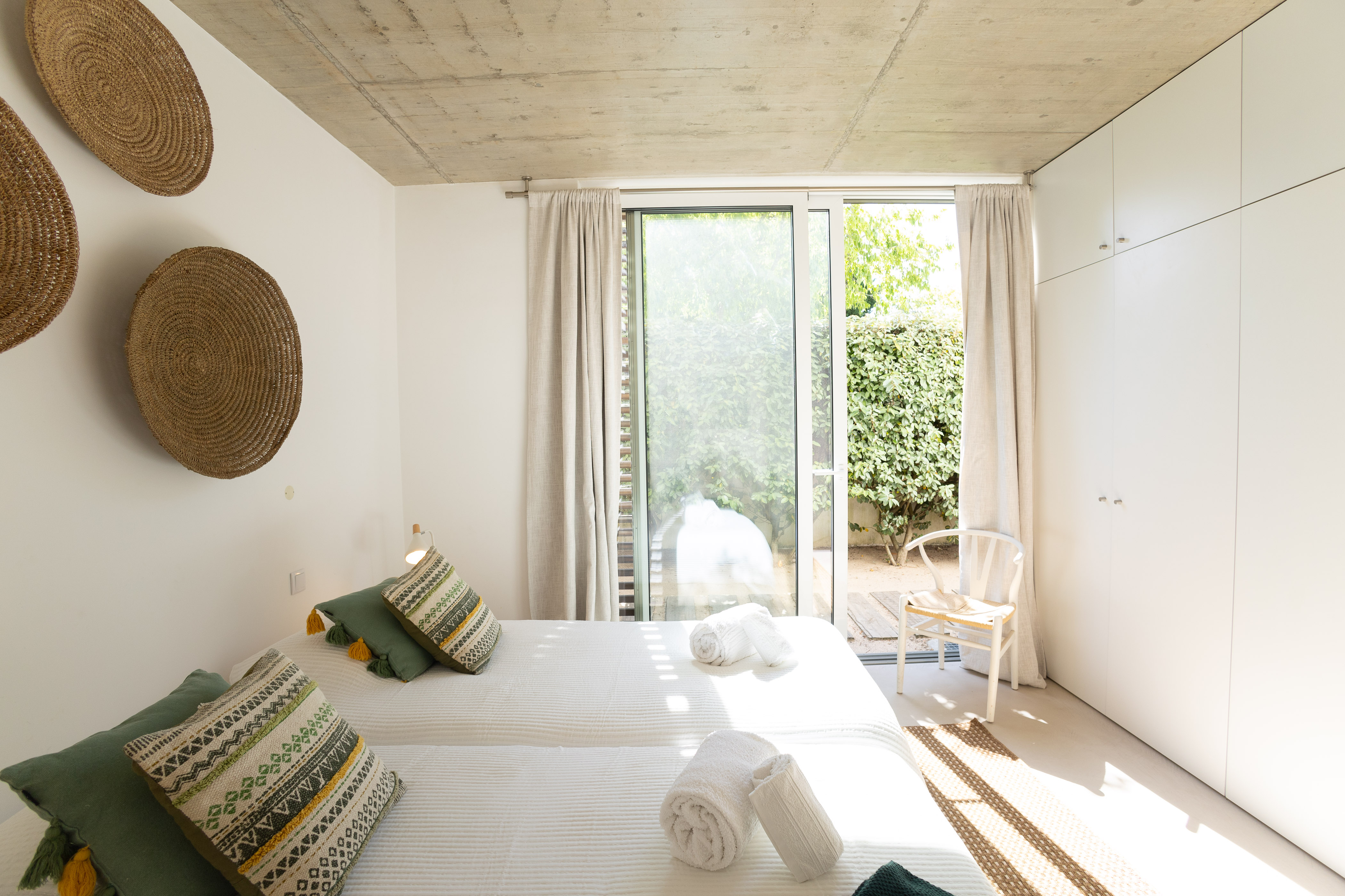 Ein freundliches Schlafzimmer mit einem großen Fenster, das Tageslicht auf das Bett fallen lässt