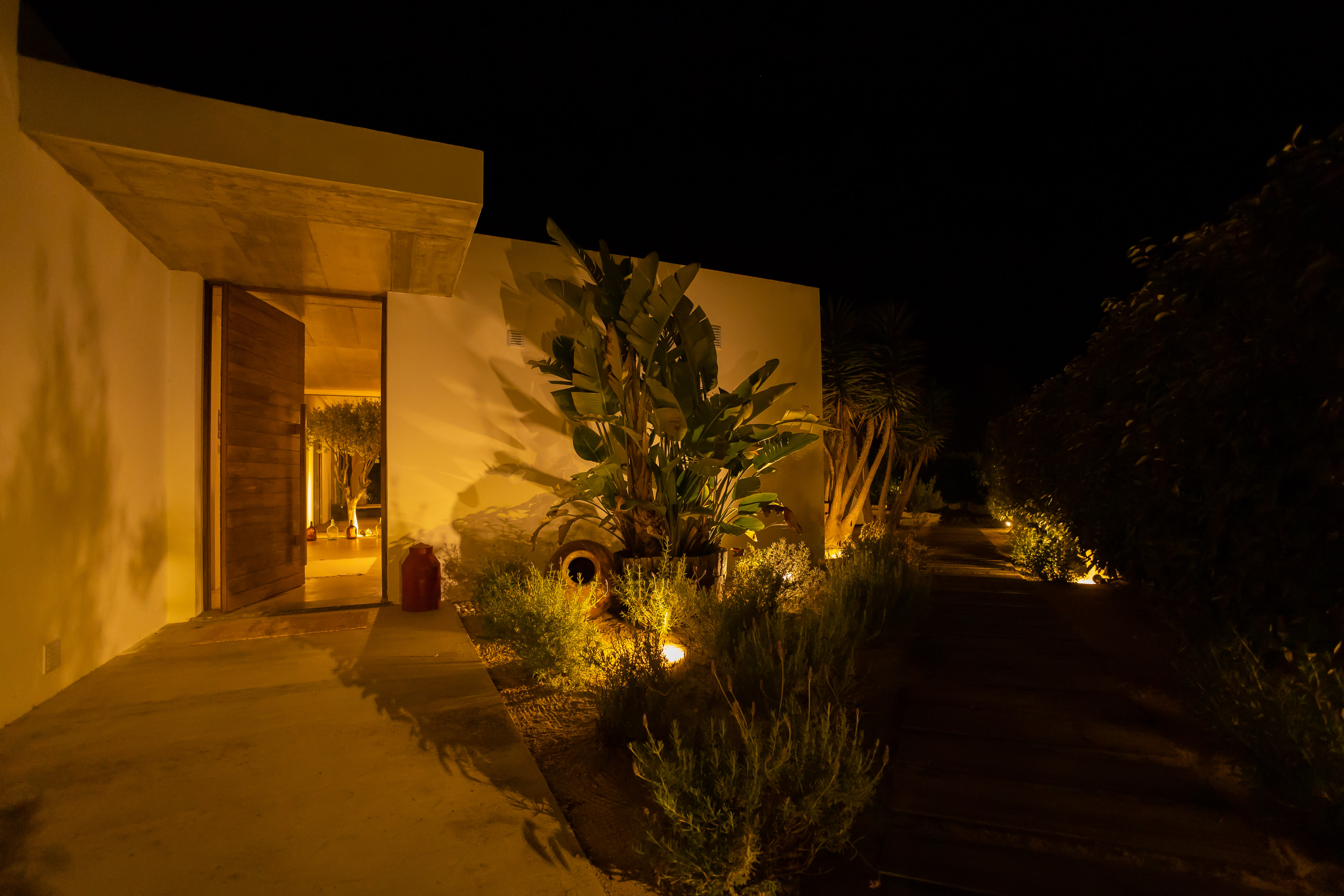 Die abendliche Beleuchtung der Villa, die den Hauseingang und die Pflanzen warm erstrahlen lässt