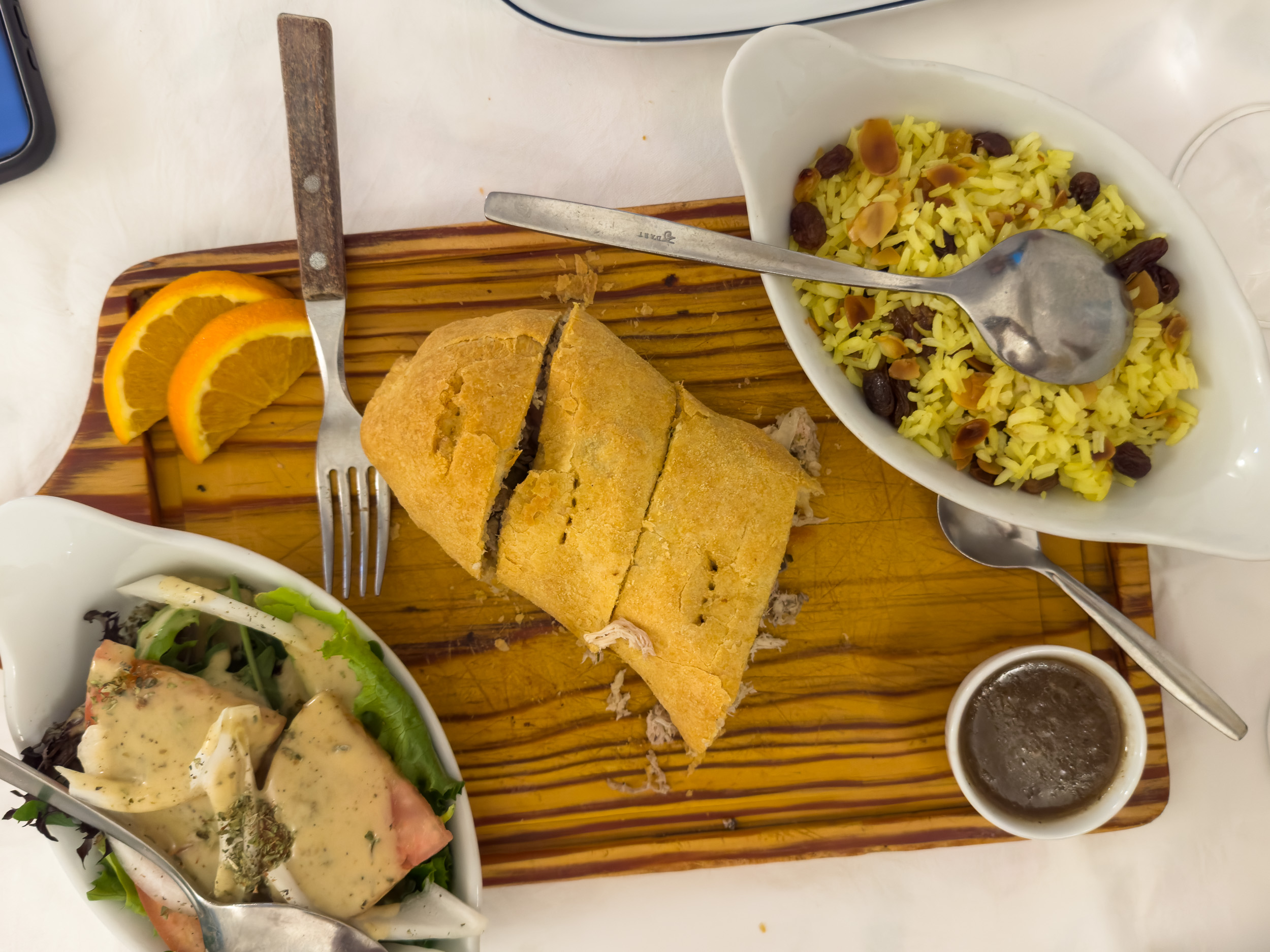 Une assiette avec une empada cuite au four dorée, servie avec du riz léger et une salade fraîche. Alentejo mettant en avant les produits régionaux locaux