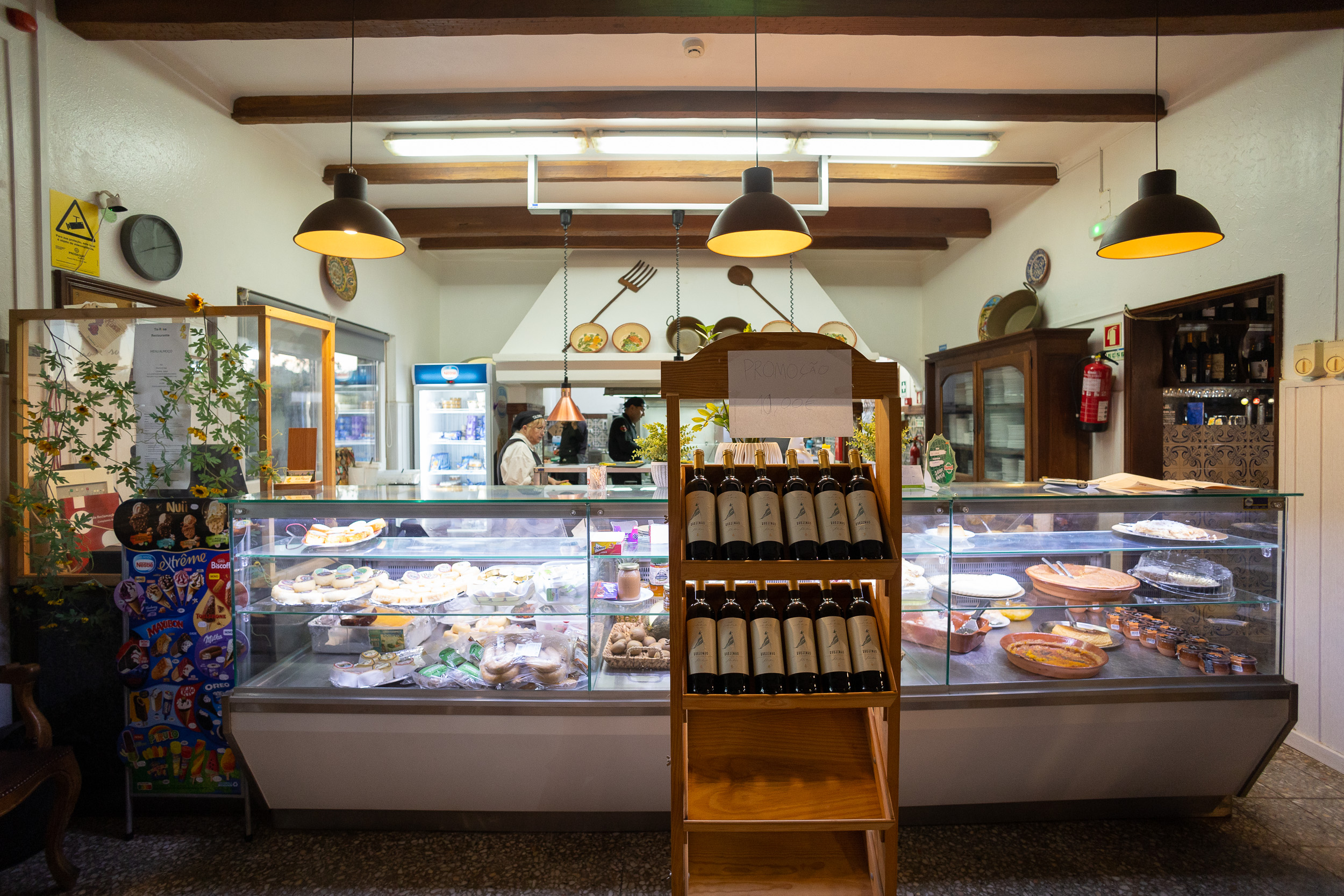 Une vitrine en verre éclairée remplie de desserts portugais traditionnels et faits maison.
