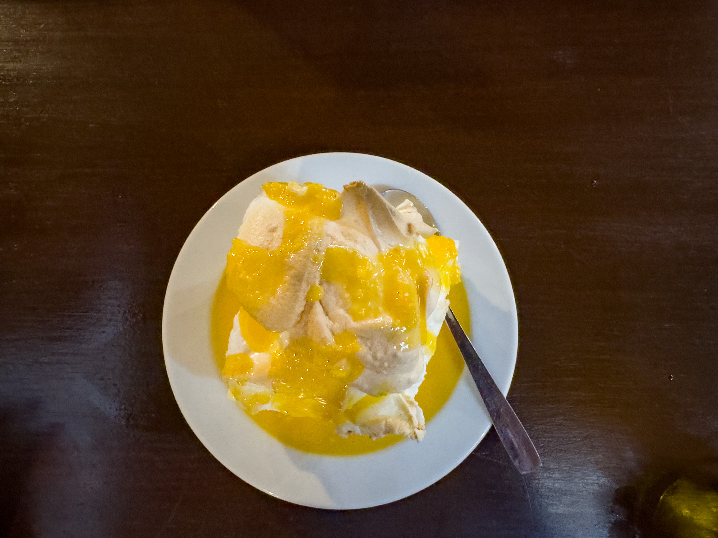 Une assiette de Farófias, un dessert portugais moelleux à base de meringue dans une crème aux œufs jaune douce.
