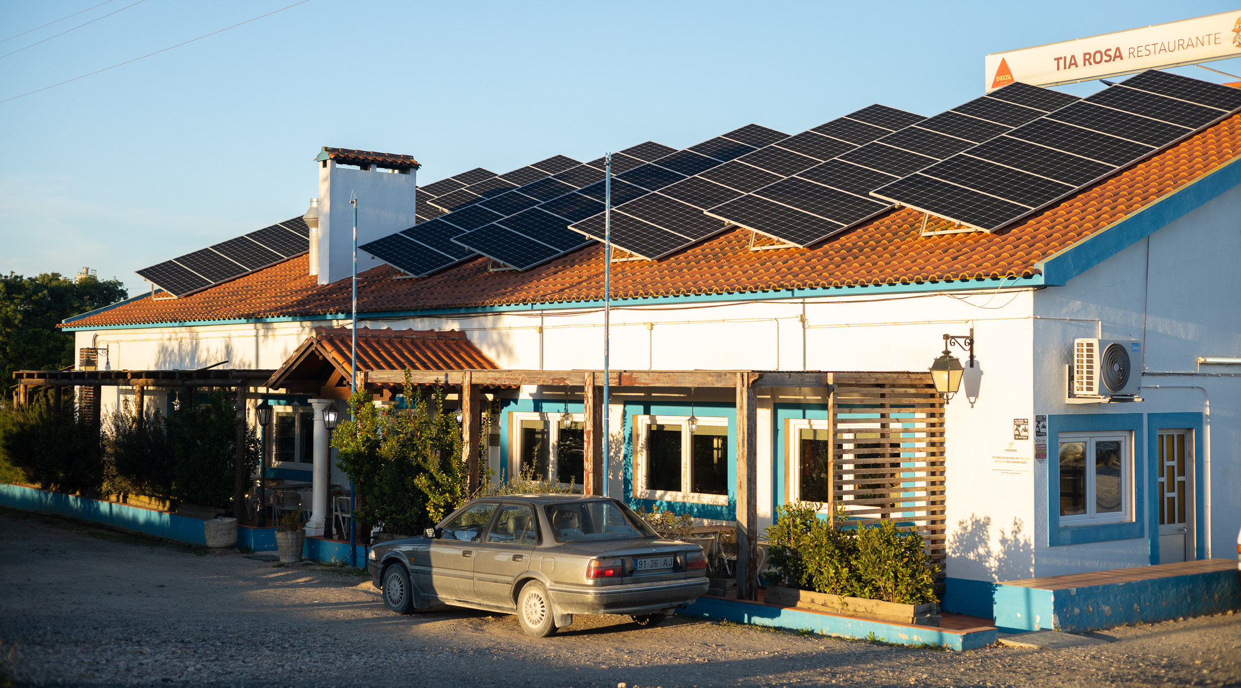 Le bâtiment de restaurant blanc et plat de Tia Rosa sous un ciel bleu, équipé de panneaux solaires sur le toit.