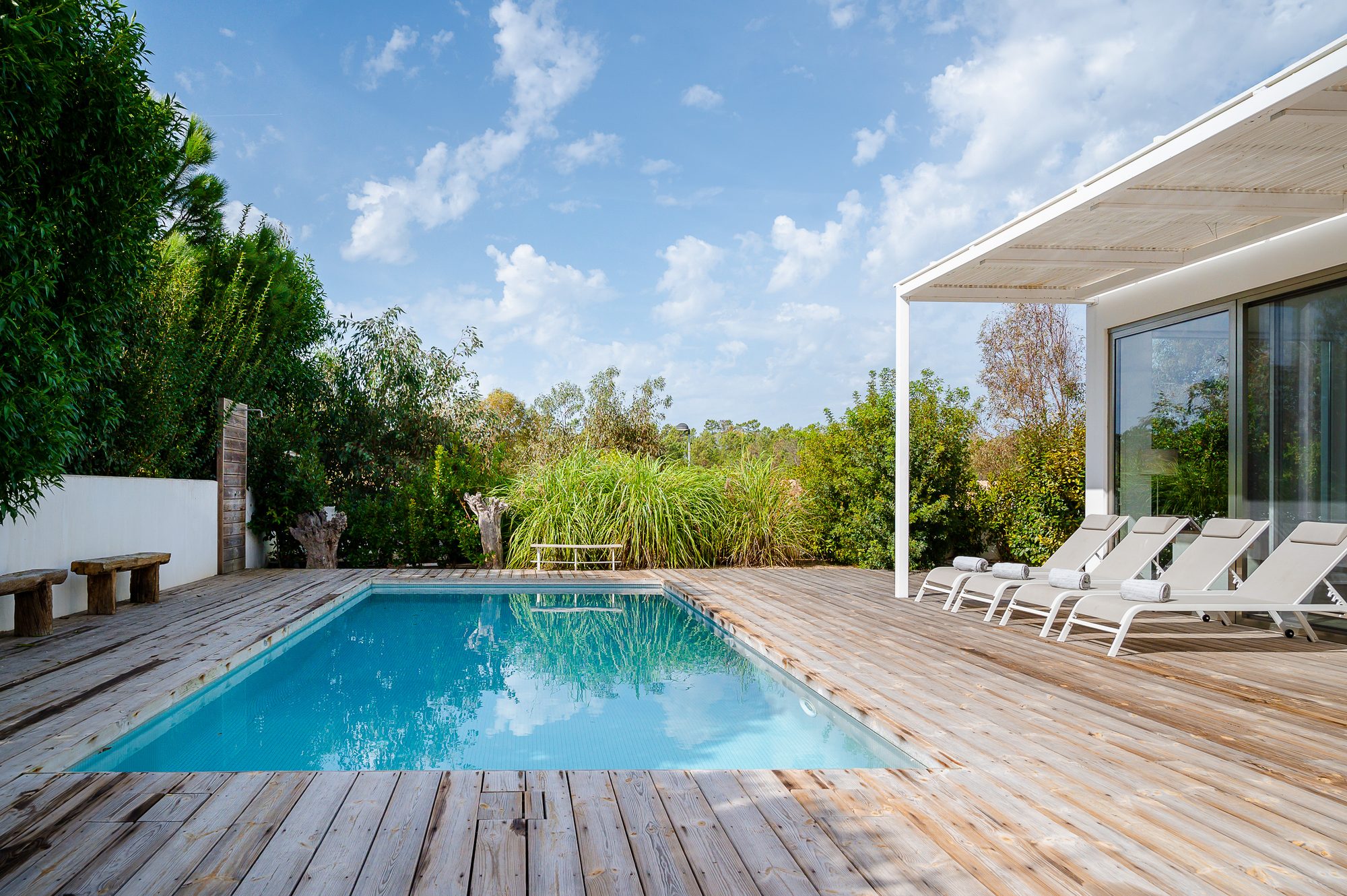 The large, blue saltwater pool of Villa Laranjeiras, surrounded by a sunny wooden deck