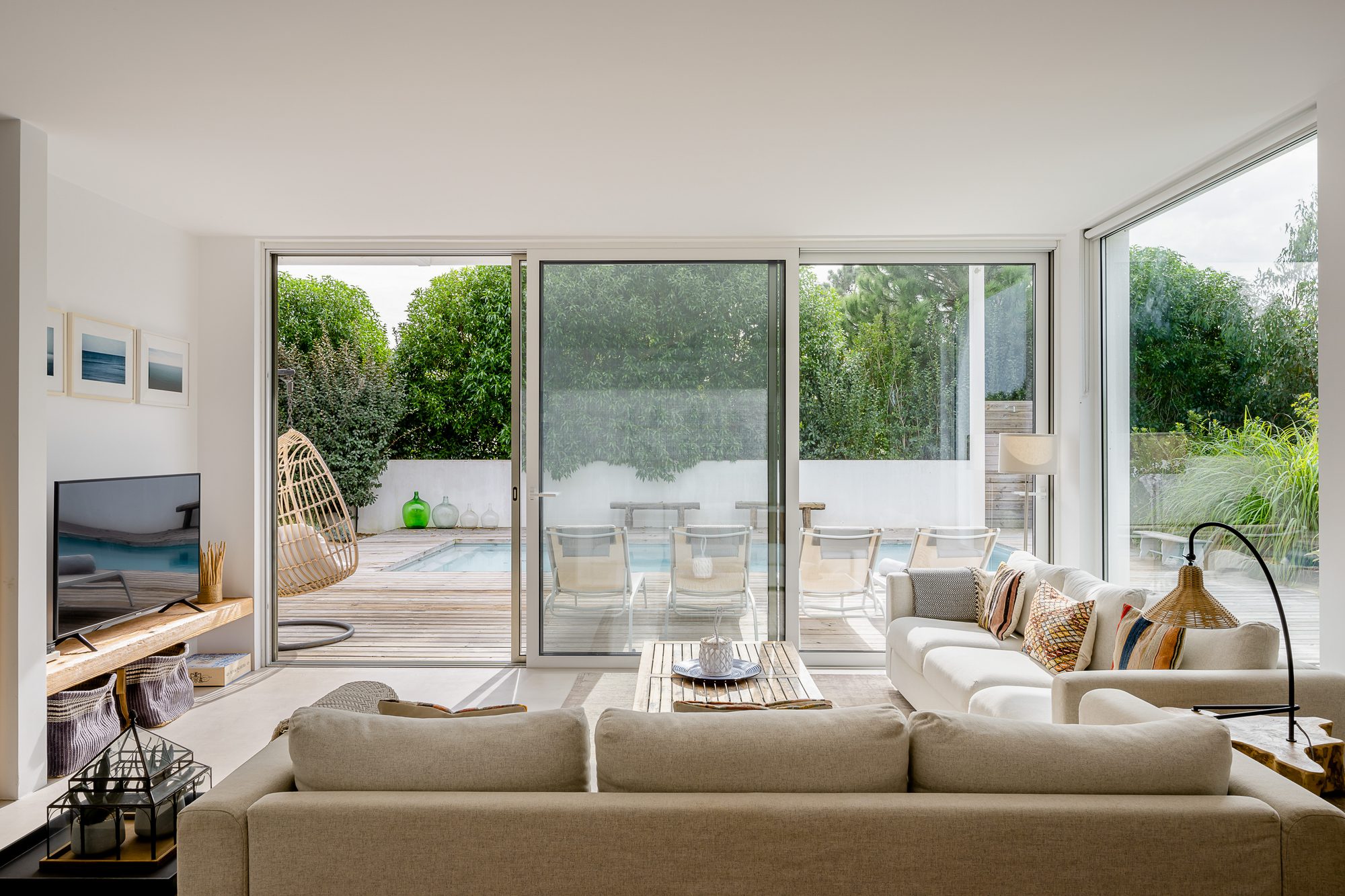 Bright, open living area of Villa Laranjeiras with large glass fronts leading to the sunny pool terrace