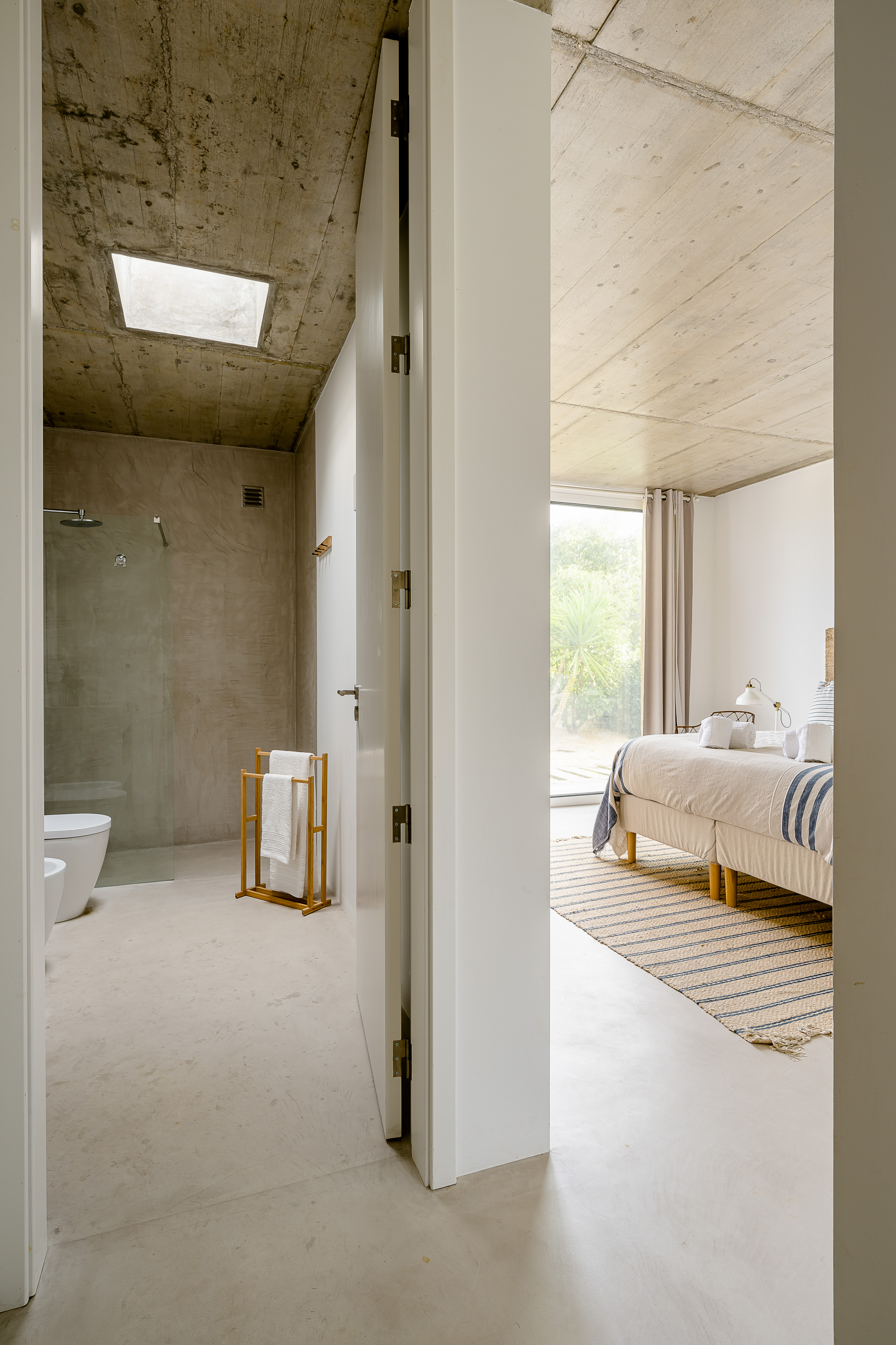 Blick vom Schlafzimmer in ein offenes, modernes Badezimmer mit freistehender Badewanne
