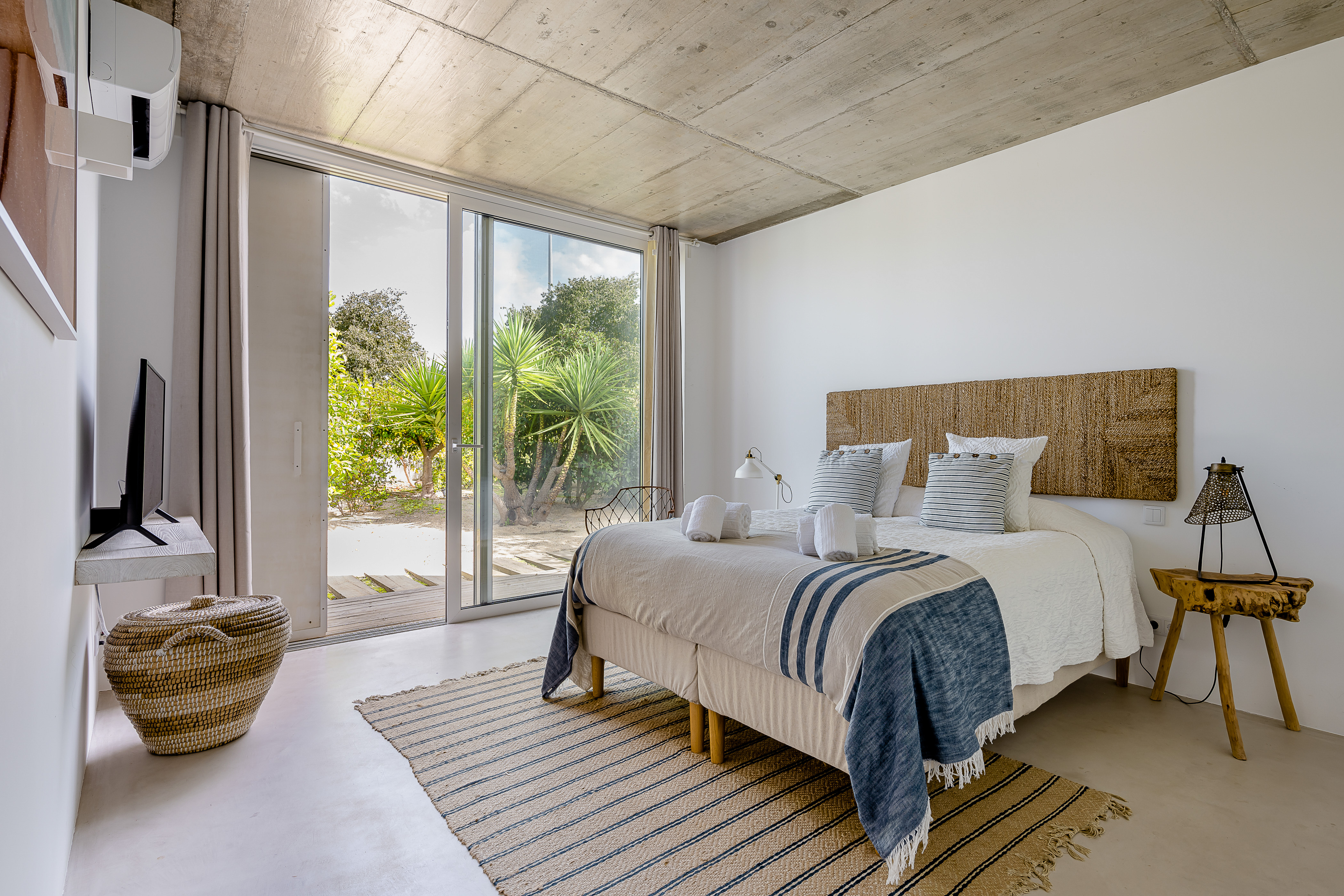 Ein geräumiges Hauptschlafzimmer im Loft-Stil mit freiliegender Betondecke und Doppelbett