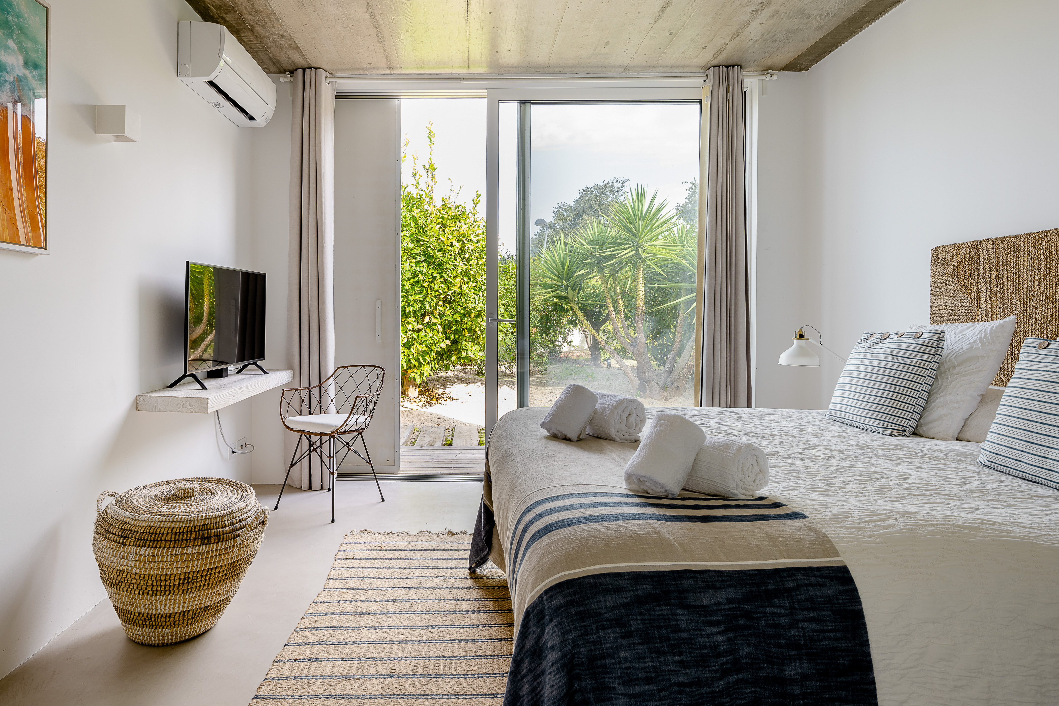 Helles Hauptschlafzimmer mit einem großen Doppelbett und bodentiefen Fenstern