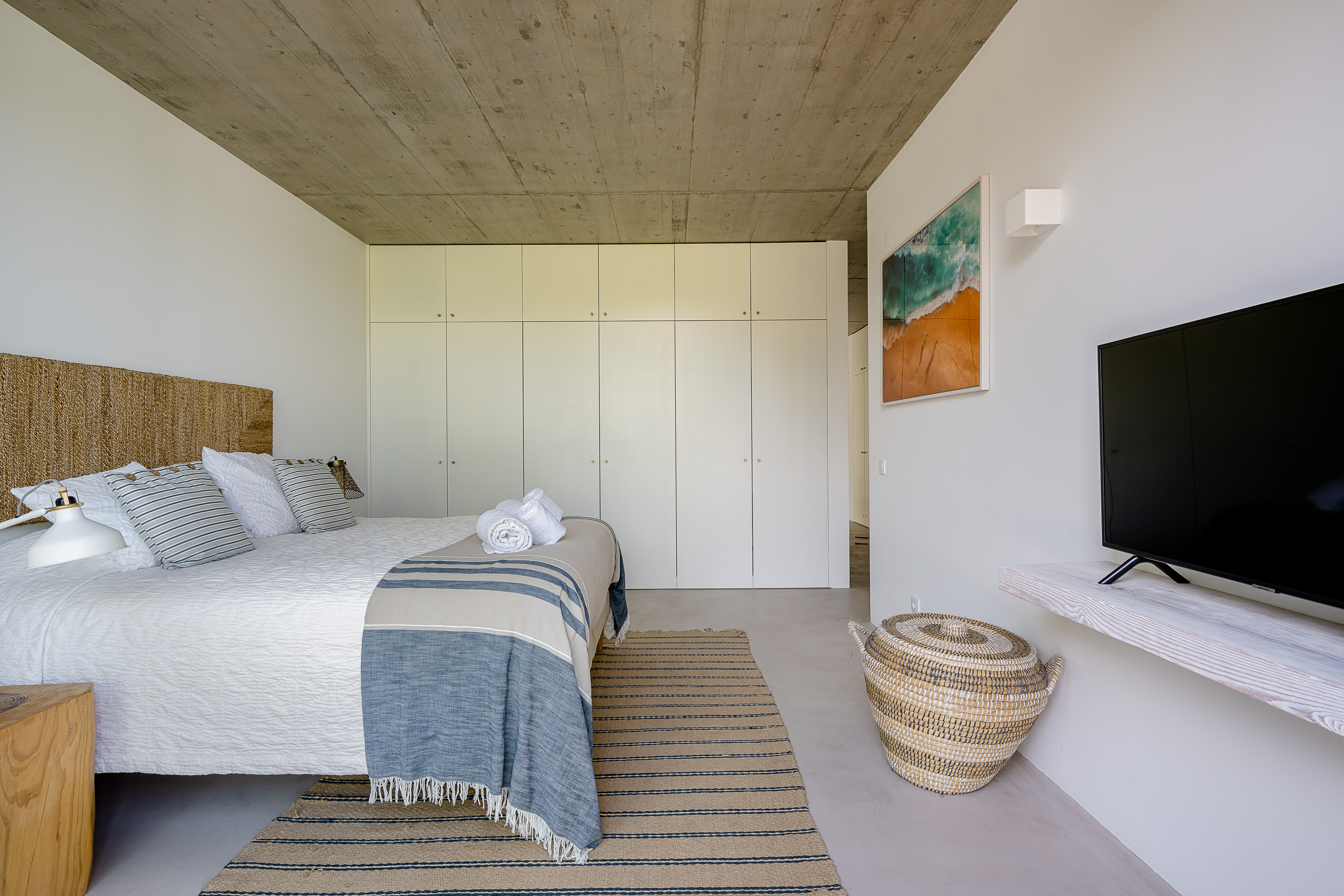 Ein großes Schlafzimmer mit Einbauschränken, Rattan-Möbeln und einem Surf-Fotokunstwerk