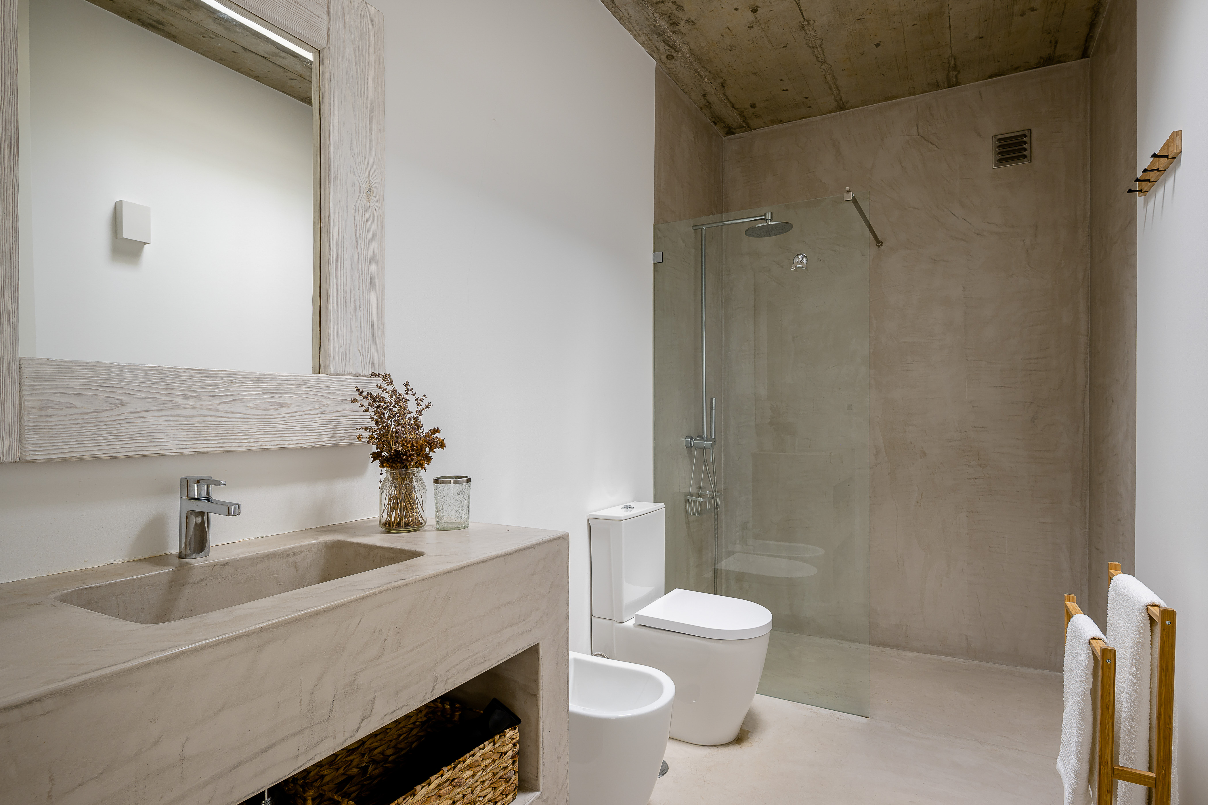 Ein elegantes Badezimmer en Suite mit modernem Waschbecken, runden Spiegeln und Sichtbeton