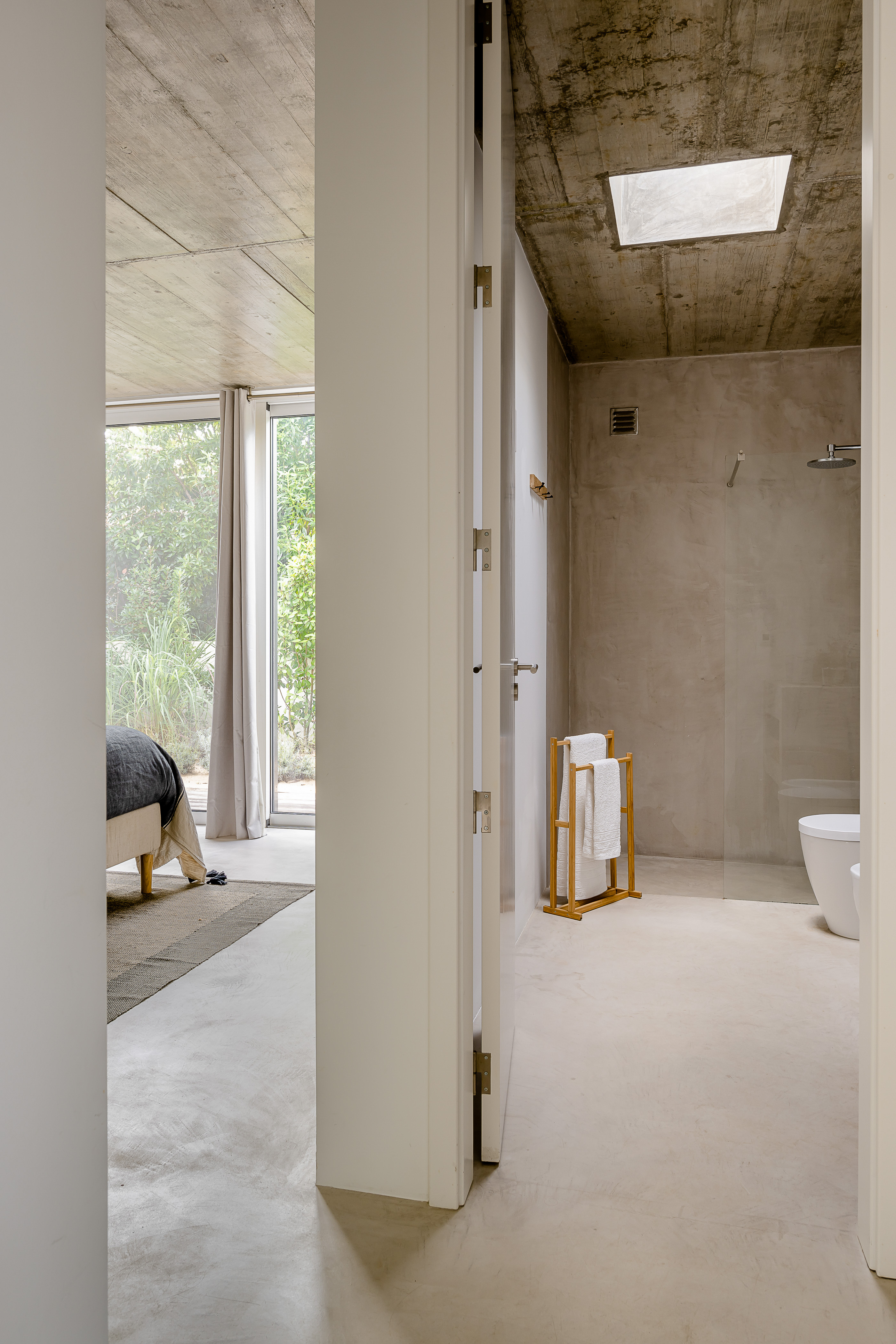 Ein offenes Bad-En-Suite mit freistehender Badewanne und Waschbecken vor einer Betonwand