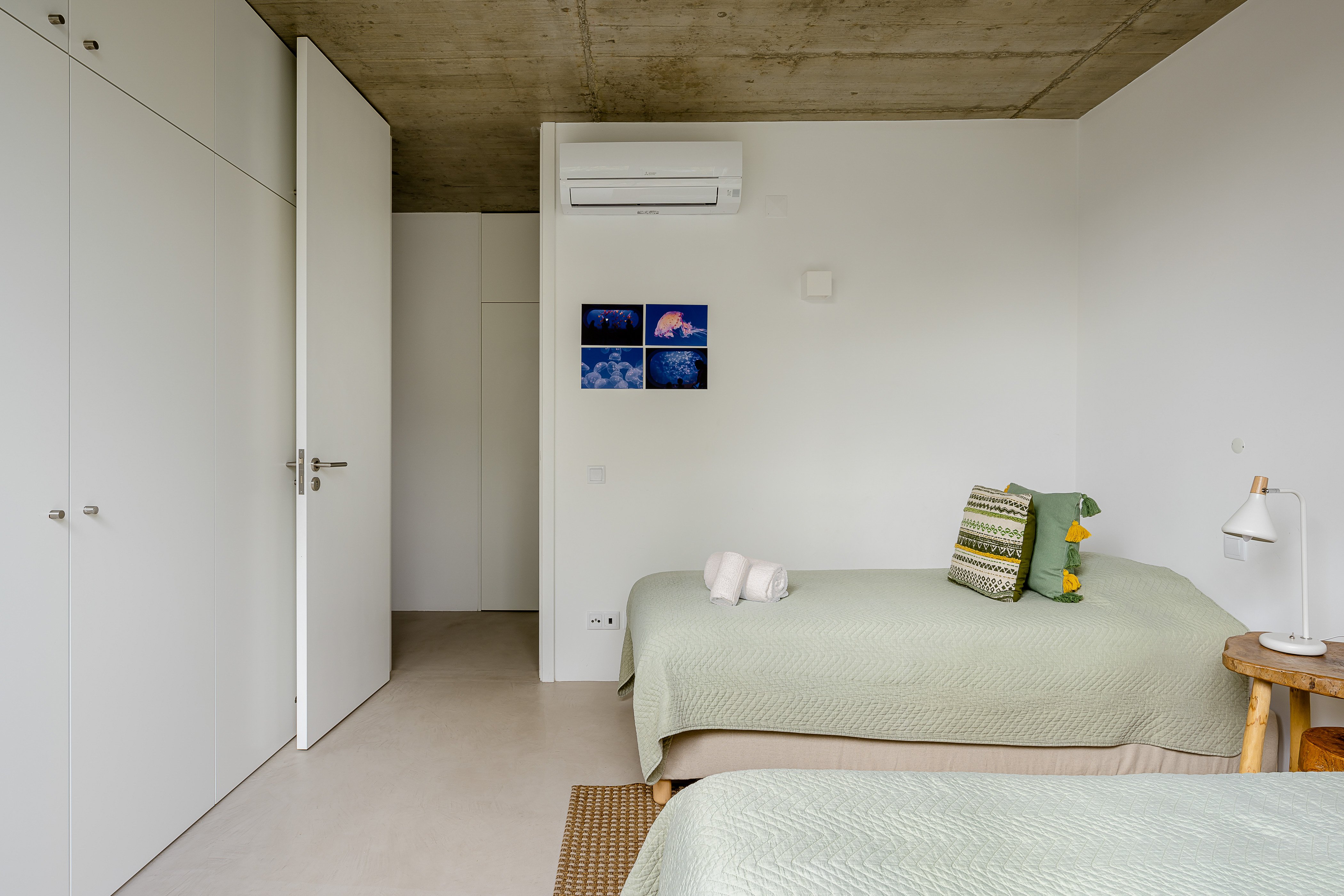 Ein ruhiges Schlafzimmer mit gemütlichem Bett, grünen Kissen und viel Stauraum
