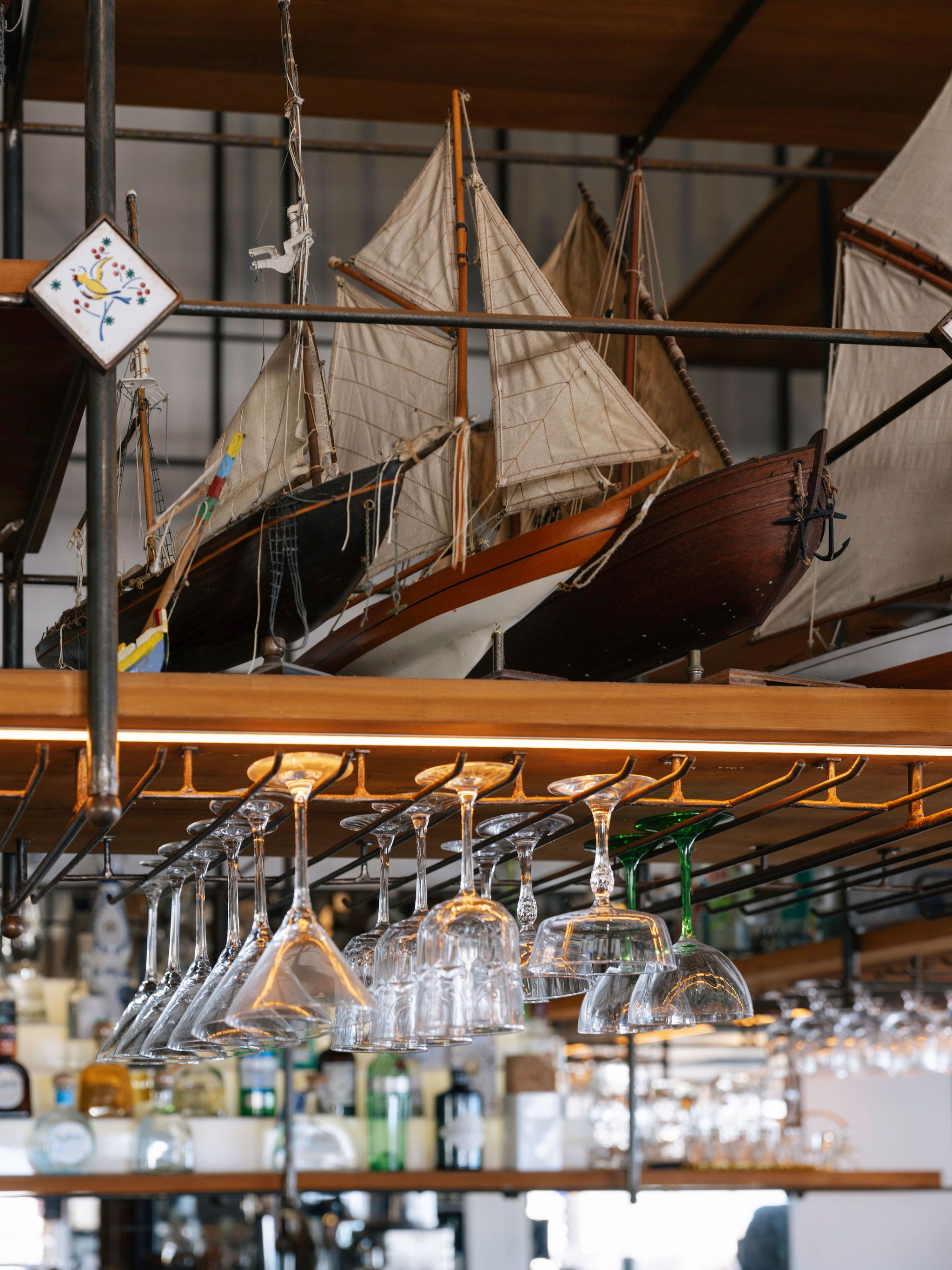 Modellschiffe über der Bar des Restaurante Sal, Comporta — maritimes Ambiente mit hängenden Weingläsern
