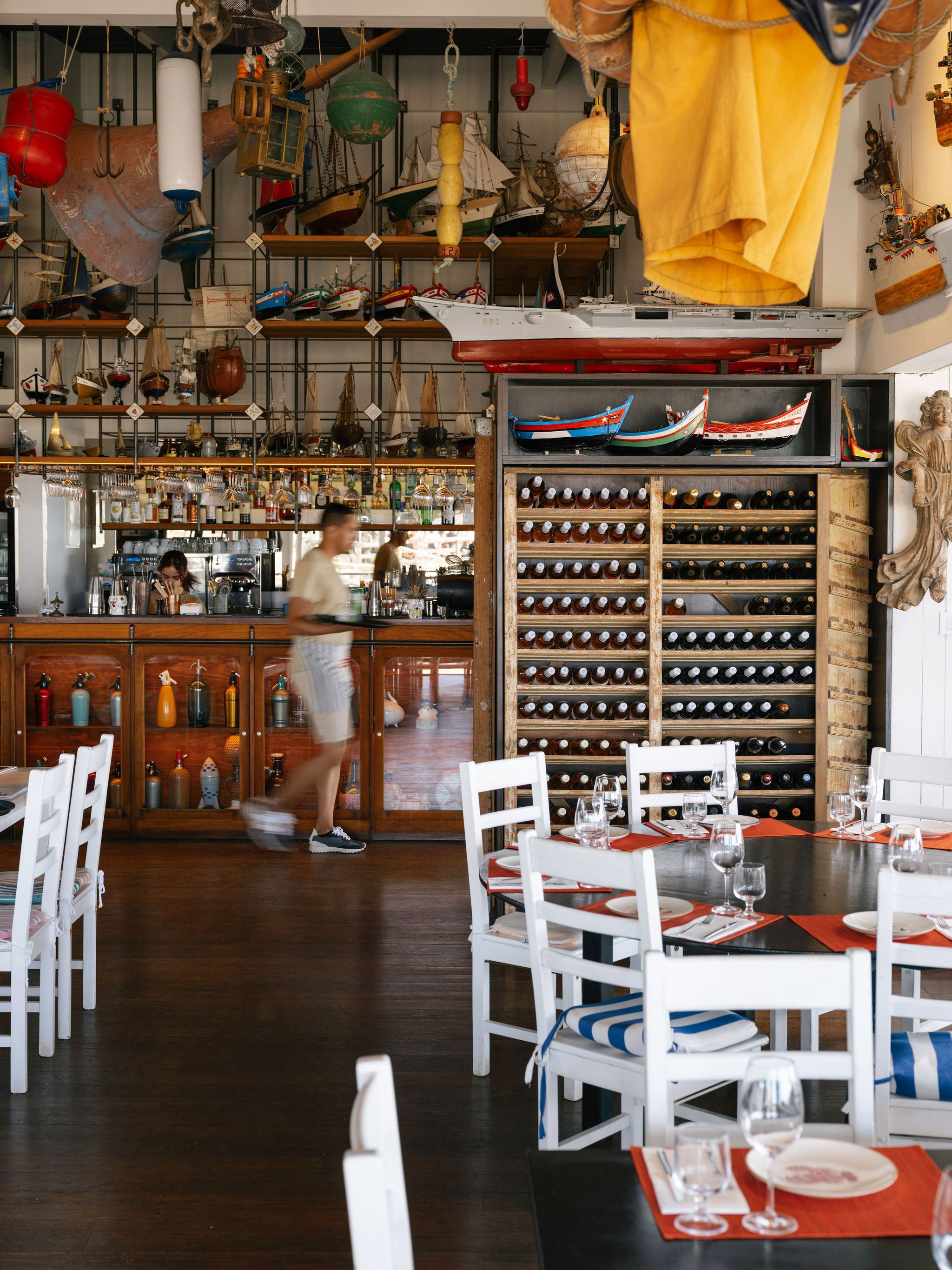 Lebendiger Mittagsbetrieb im Restaurante Sal — gedeckte Tische, Weinregal und Schiffsmodell-Sammlung