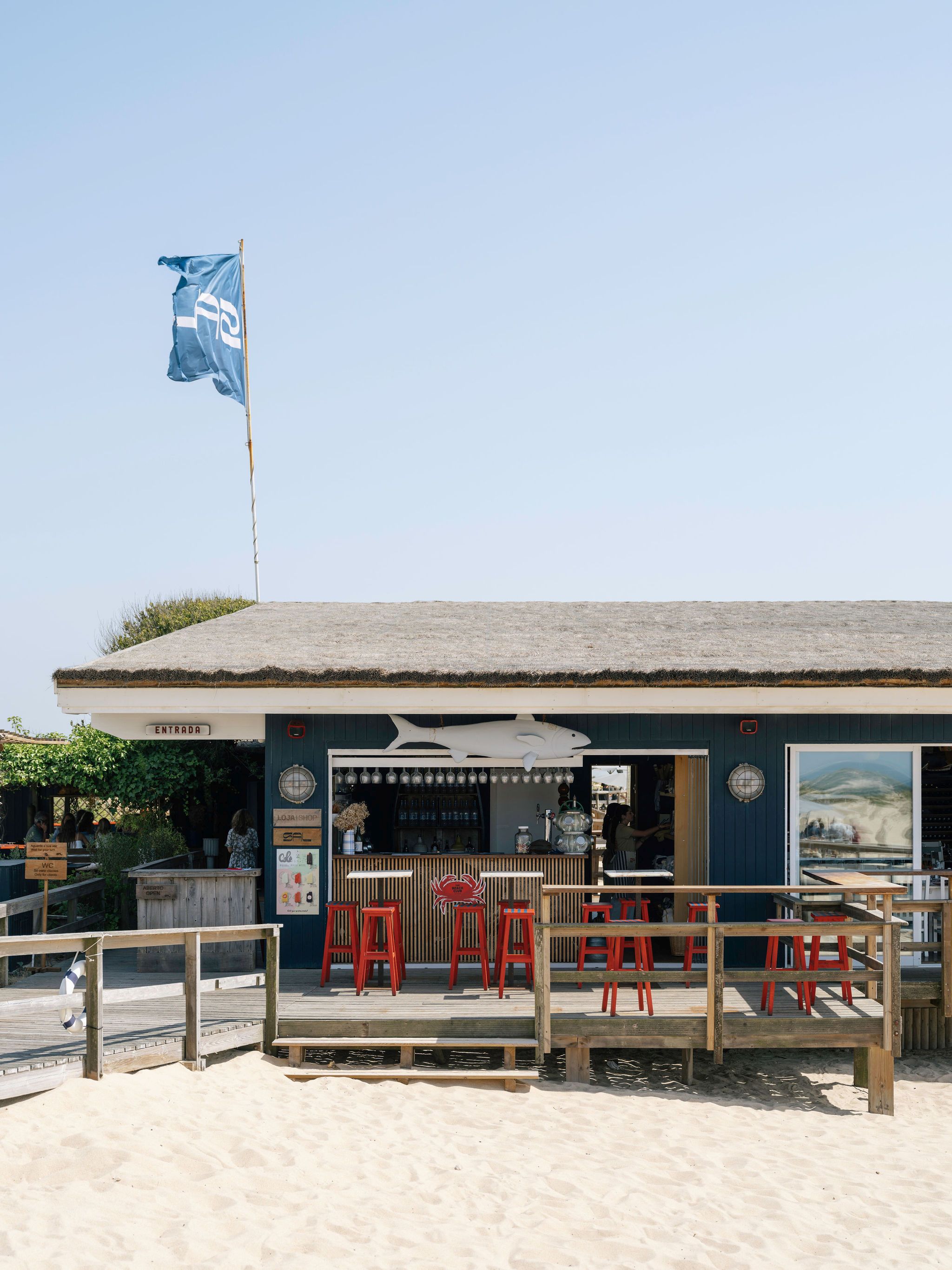 Außenansicht des Restaurante Sal — blaue Holzfassade mit Strohdach direkt am Sandstrand von Comporta